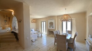 Un salón amplio con una mesa de comedor, sillas de mimbre y una chimenea.