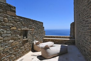 Ein Sitzbereich im Freien mit Steinwänden und Blick auf das Meer.