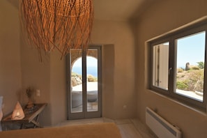 A bedroom with a large window, a door leading outside, and a woven light fixture. - Dioni Tinos, sea view elegant villa (Kardiani)