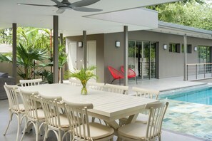 A poolside area with a table and chairs, a ceiling fan, and a view of the pool. - Spacious 4-bedroom house in beautiful Playa Langosta Tamarindo . (Playa Langosta/ Tamarindo)
