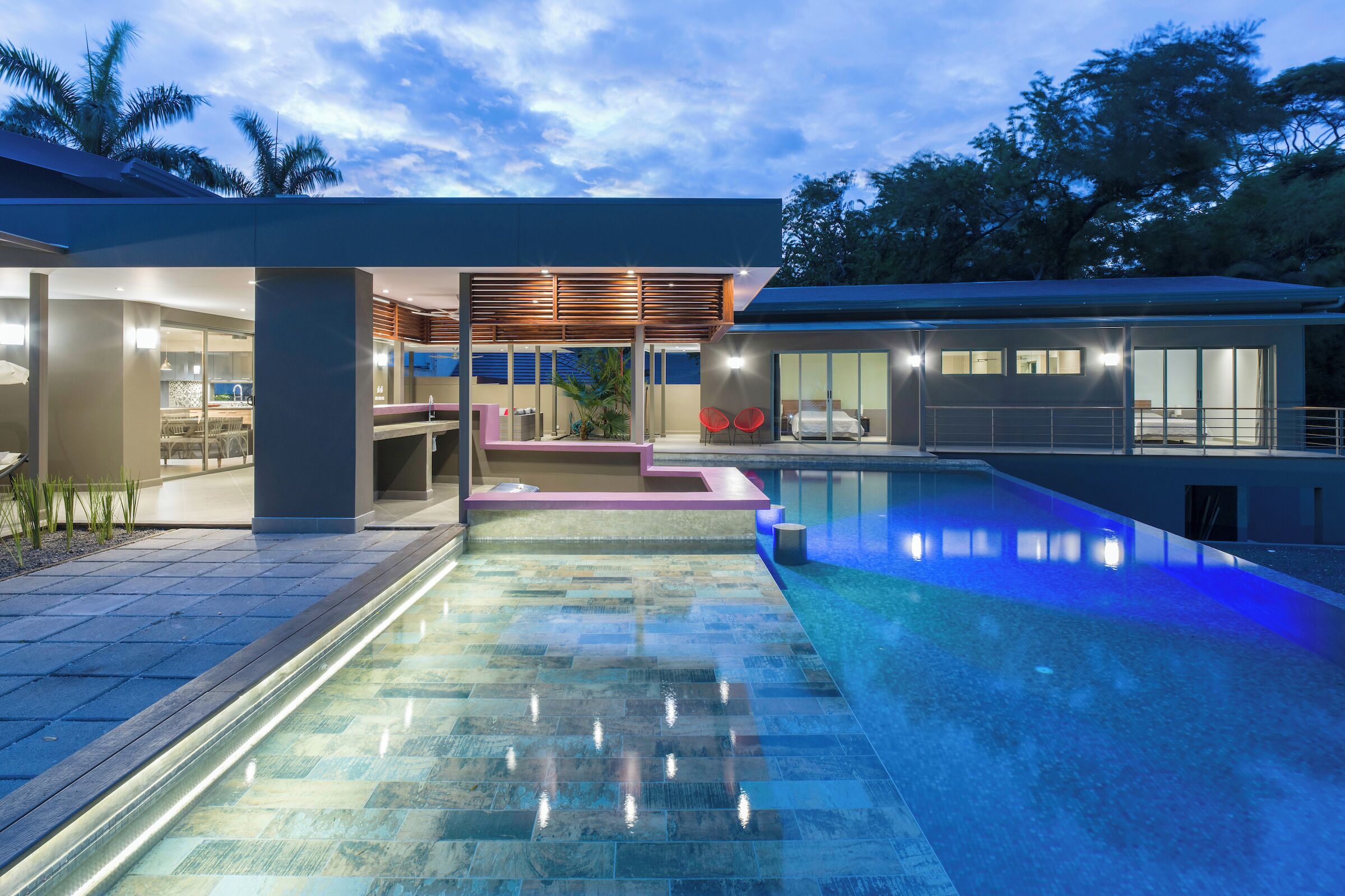 Ein modernes Haus mit Swimmingpool, überdachter Terrasse und Essbereich.