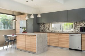 A modern kitchen with a central island, grey cabinets, and a patterned backsplash. - Spacious 4-bedroom house in beautiful Playa Langosta Tamarindo . (Playa Langosta/ Tamarindo)