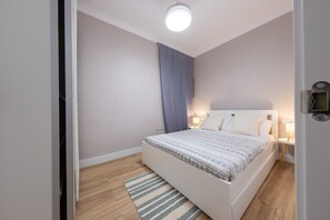 Ein modernes Schlafzimmer mit Bett, Nachttischlampen, Holzboden und Deckenleuchte.