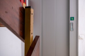 A door with a green sign indicating room number 1, a light switch, and a wooden structure partially visible. - Alma Canteras Vacation Apartment with Sea Views and Wi-Fi (Las Palmas de Gran Canaria)