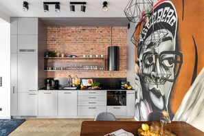 A modern kitchen with a brick wall, stainless steel appliances, and a mural. - Helska 11 - Apartamenty blisko plaży  (Sopot)
