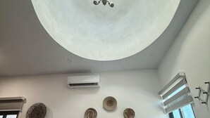 Un dormitorio con cama, lámpara de techo, equipo de aire acondicionado y paneles decorativos en la pared.