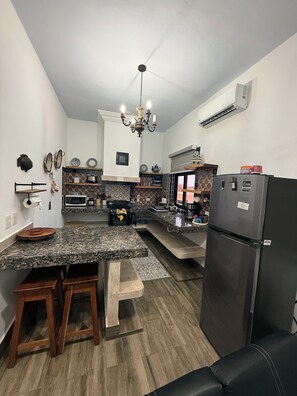 Eine Küche mit Granit-Arbeitsplatten, einem schwarzen Kühlschrank und einer Kristallleuchtre.