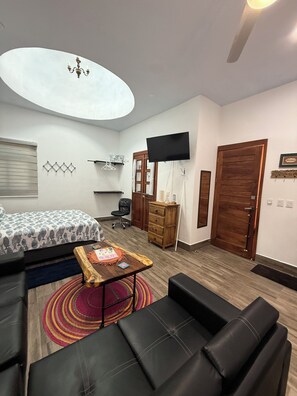 A modern living room with a sofa, a coffee table, a TV, and a bed with a patterned bedspread. - Peaceful 1-bedroom studio with AC in Isla Mujeres (Isla Mujeres)