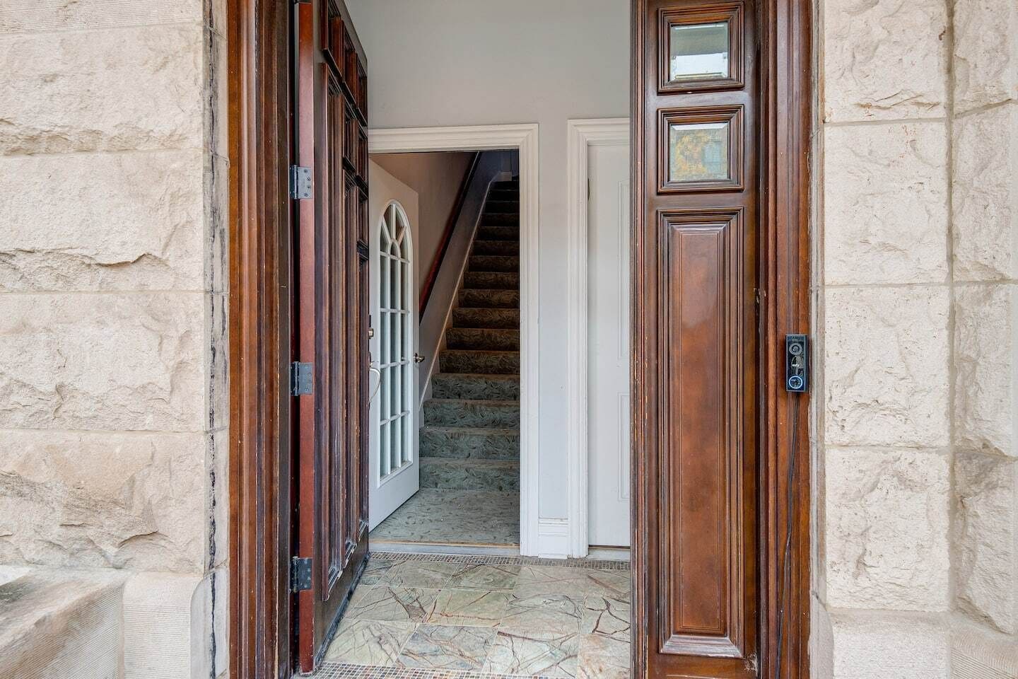 A stone wall, a wooden door, and a staircase leading to an upper floor.