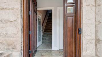 A stone wall, a wooden door, and a staircase leading to an upper floor.