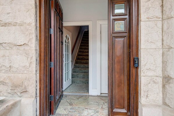 A stone wall, a wooden door, and a staircase leading to an upper floor.