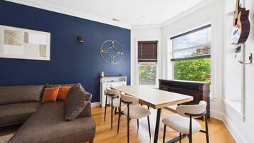 Una sala moderna con una pared azul decorativa, una mesa de comedor de madera y un sofá gris.