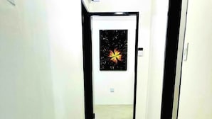 Un passadís amb un paviment amb relleu que condueix a una porta amb un quadre emmarcat.
