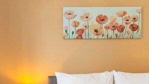 Ein Hotelzimmer mit einem Bett, einer Nachttischlampe und einem Blumenbild an der Wand.