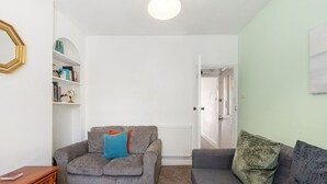 Ein Wohnzimmer mit grauem Sofa, einem Holztisch und einem Bücherregal.