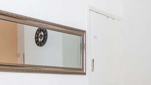Ein Holztisch mit Stuhl vor einer weißen Wand, darüber ein Spiegel.