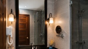A modern bathroom with a large mirror, a white sink, and a glass-enclosed shower.