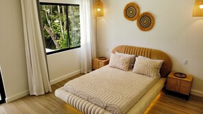 A bedroom with a large bed, two bedside tables, a window with curtains, and wall-mounted lamps. - Brand New Modern  5 Bed 4.5 Bath Pool home with huge rooftop terrace (Uvita)