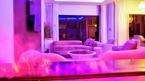Un salon moderne avec un ensemble de canapés, une table basse et une grande fenêtre agrémentée de rideaux.