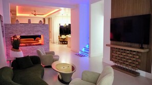 Un salon moderne doté d’une cheminée, d’un coin salon et d’un téléviseur à écran plat fixé sur un panneau en bois.