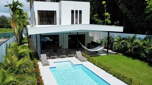 A modern two-story house with a swimming pool, outdoor seating, and a hammock. - Brand New Modern  5 Bed 4.5 Bath Pool home with huge rooftop terrace (Uvita)