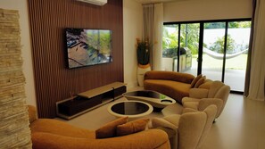 A modern living room with a flat-screen TV, comfortable sofas, a coffee table, and a view of the outdoors through large windows. - Brand New Modern  5 Bed 4.5 Bath Pool home with huge rooftop terrace (Uvita)