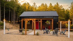 A rustic cabin with a metal roof, a red door, and outdoor seating. - Secluded Cabin Retreat - Fast internet - Fire Pit (Summerville)