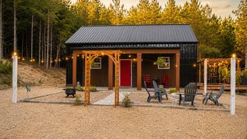 A rustic cabin with a metal roof, a red door, and outdoor seating.