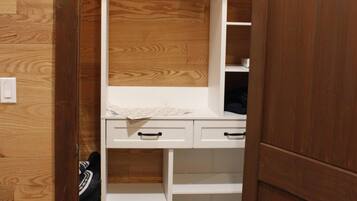 A walk-in closet with wooden flooring, white shelving, and a mirror.