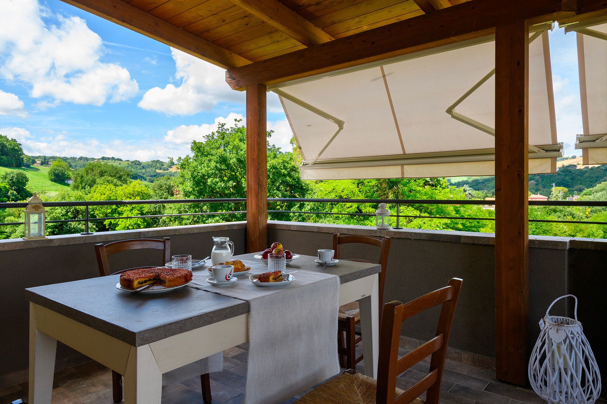 A table set for breakfast with a scenic view, wooden chairs, and a white lantern.
