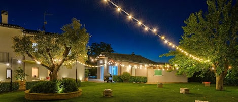 Un patio con un edificio, luces colgantes y árboles.