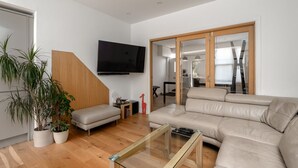 Ett modernt vardagsrum med en soffa, ett soffbord i glas och en tv som är monterad på väggen.