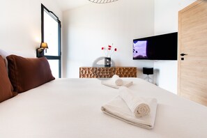 Ein Hotelzimmer mit Bett, Fernseher, einem Holz-Kopfteil und einem an der Wand befestigten Fernseher.
