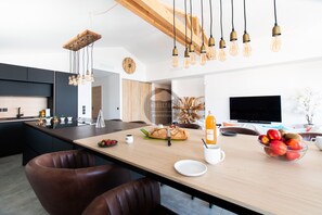 Una cocina moderna con una isla central, lámparas colgantes y un televisor de pantalla plana.