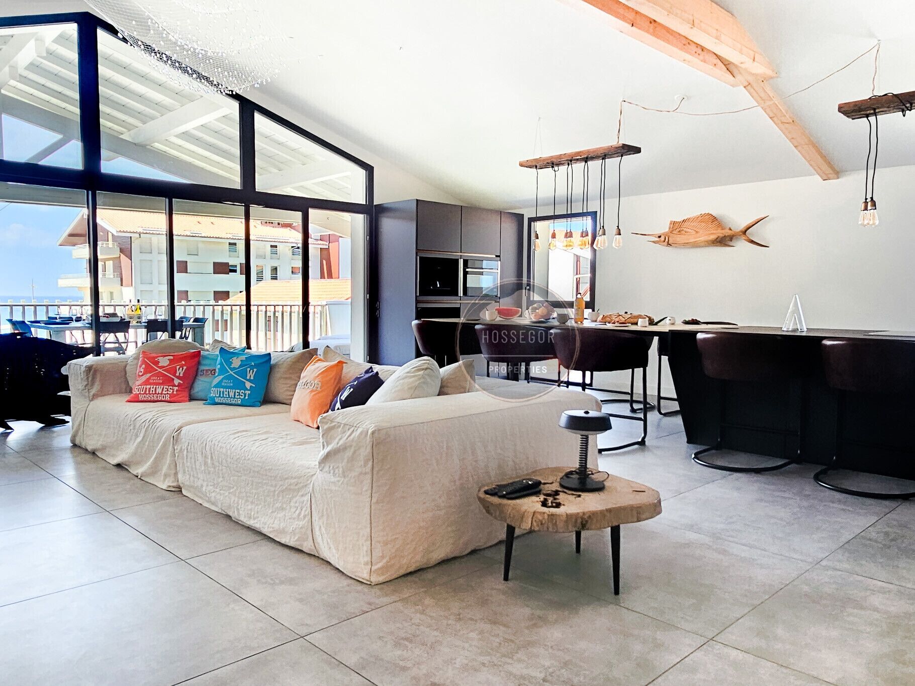 A modern living room with a sofa, a coffee table, and a dining area with chairs and a bar.