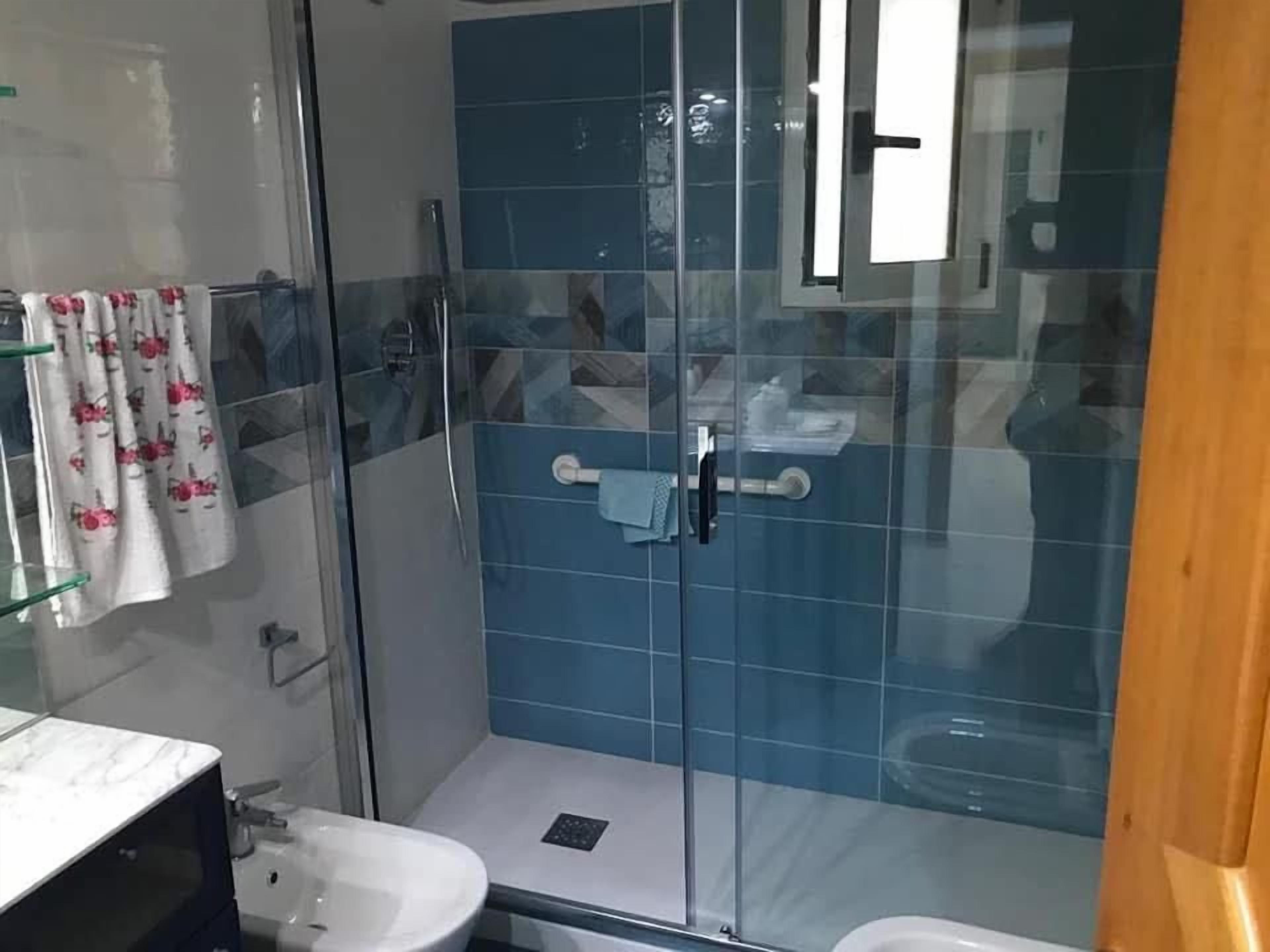 A bathroom with a glass-enclosed shower, a sink, and a toilet.