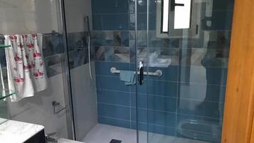 A bathroom with a glass-enclosed shower, a sink, and a toilet.
