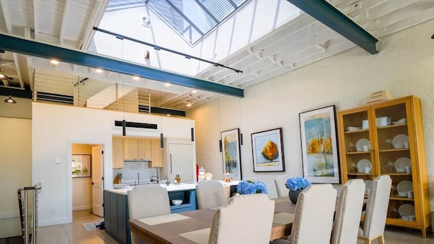 A modern interior with a dining area, kitchen, and a skylight.