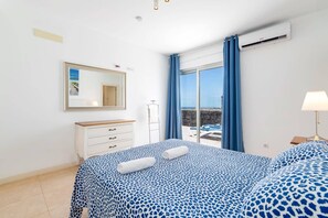 Een slaapkamer met een bed, een kaptafel, een spiegel en een raam voorzien van gordijnen.