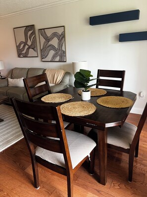 A dining area with a dark wooden table, woven placemats, and matching chairs. - Sunsets, sand & Style - Naples Getaway (Naples)
