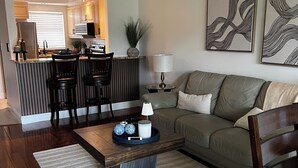En moderne stue med sofa, sofabord og et køkken i baggrunden.