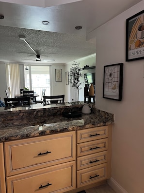 A kitchen with a granite countertop, wooden cabinets, and a ceiling fan. - Sunsets, sand & Style - Naples Getaway (Naples)