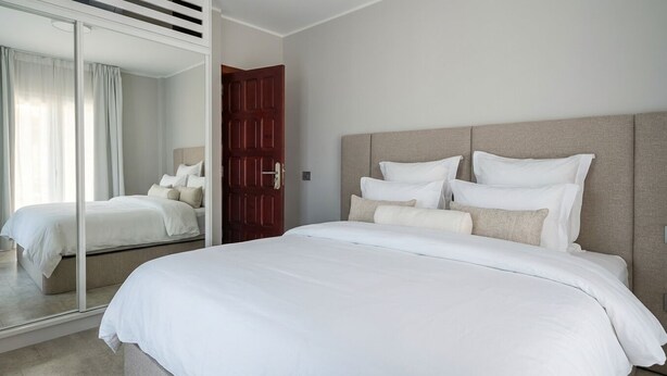 A hotel room with a large bed, a wooden door, and a mirror reflecting the room. - Exclusive Mountain Villa (Barranco Hondo)