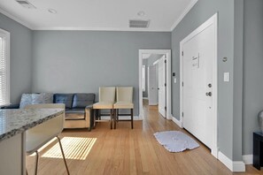 A modern living room with a sofa, chairs, a coffee table, and a kitchen area with a countertop. - Enjoyable 3-bedroom apartment with AC in vibrant Somerville (Somerville)