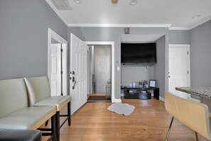 A hallway with a bench, a door, and a television in the background. - Enjoyable 3-bedroom apartment with AC in vibrant Somerville (Somerville)