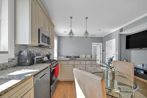 A modern kitchen with granite countertops, stainless steel appliances, and a glass dining table. - Enjoyable 3-bedroom apartment with AC in vibrant Somerville (Somerville)