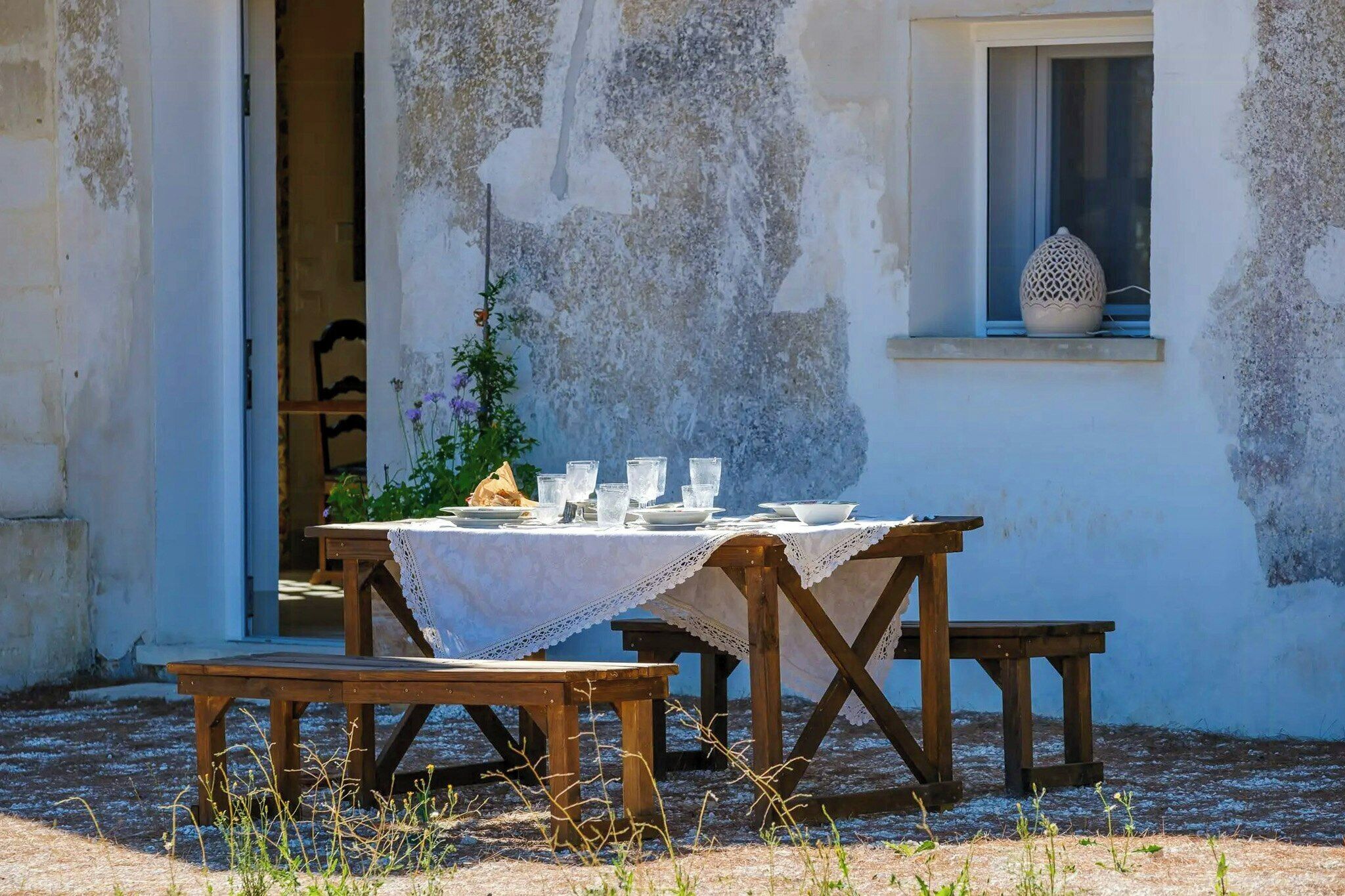 Un área de comedor al aire libre con una mesa dispuesta para dos personas, rodeada de bancos de madera.