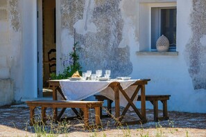 An outdoor dining area with a table set for two, surrounded by wooden benches.