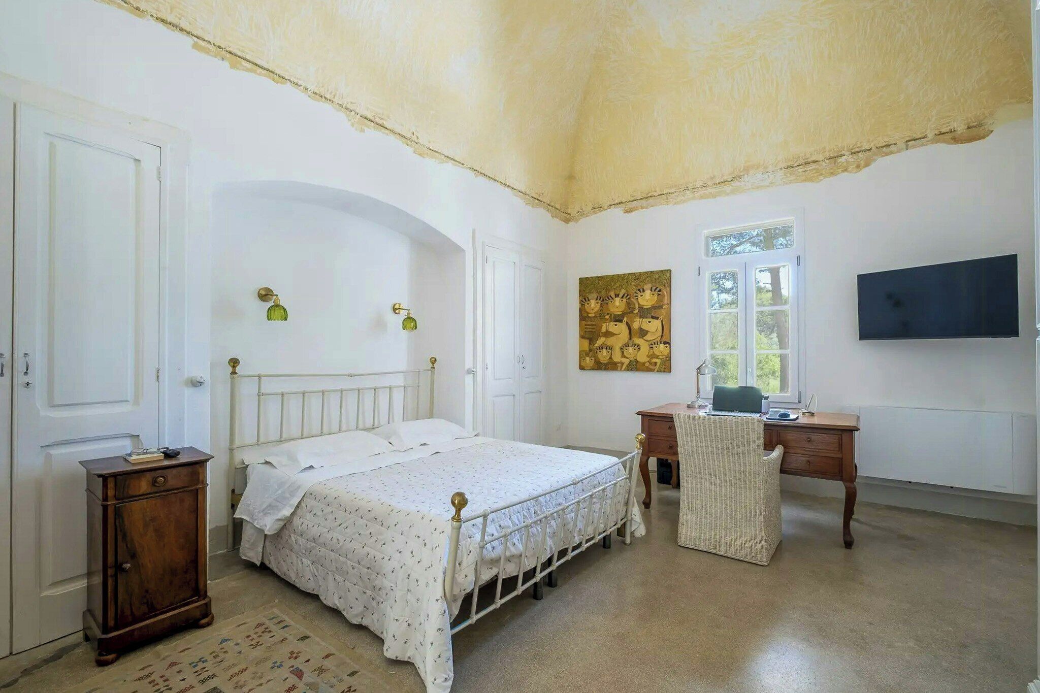 Una camera da letto con un letto, una scrivania, una sedia, un armadio e un quadro appeso al muro.