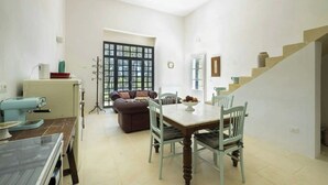 Uma sala de estar espaçosa com uma mesa de jantar, cadeiras, um sofá e uma escada.